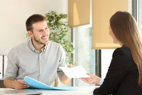 Man giving a resume to the interviewer in a job interview in a desktop at office